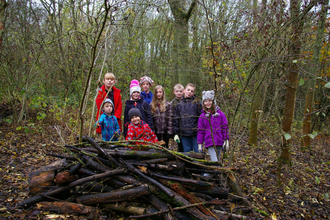 A group of children in front of a log pile