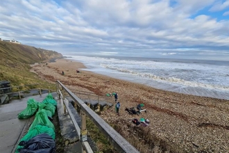 view of collected litter next to pebble beach with sea in distance