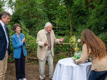People in woodland looking delighted at celebration cake on a table