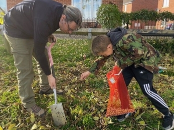 Man and boy digging greenspace outside houses