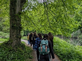 Back of a group of people walking along a tarmac path with woodland on sides