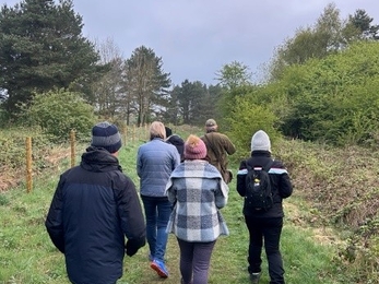 the backs of a group of people walking on path with woodland on either side
