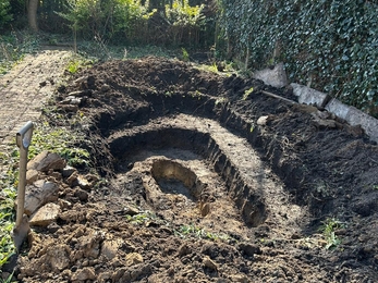 A garden dug up with the shape of a pond forming