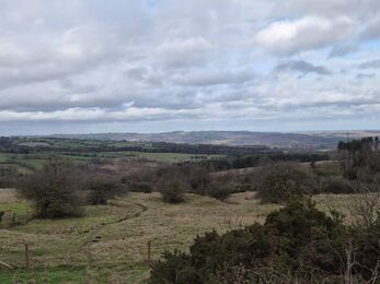 landscape view of fields and woodlands with partly cloudy sky