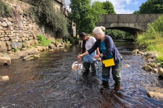Two women sampling the water in the River Wear for plastic