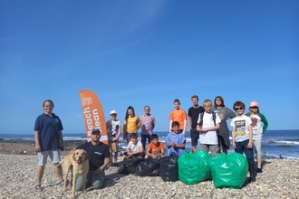 Group on beach with litter pick bags