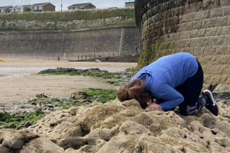 Young person listening to rocks on beach