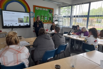 young people in classroom looking towards presentation on screen