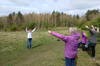 Group of people in open green space with arms in air