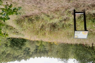 View over meadow with trees in background and sign in foreground