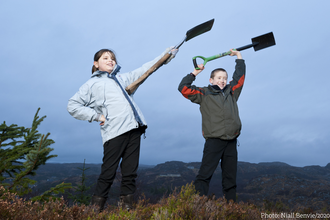 Children holding spades on moorland.