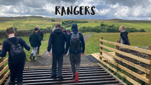 young people walking across cattle grid towards field