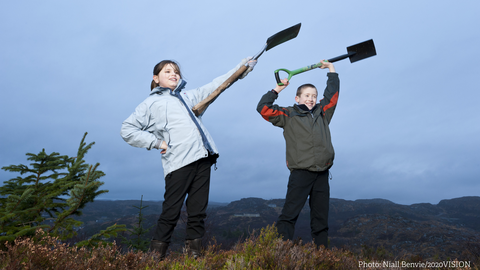 Children holding spades on moorland.