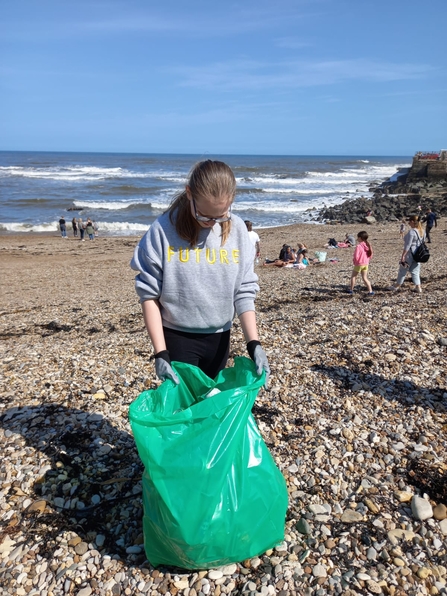 Girl on beach with bag of litter