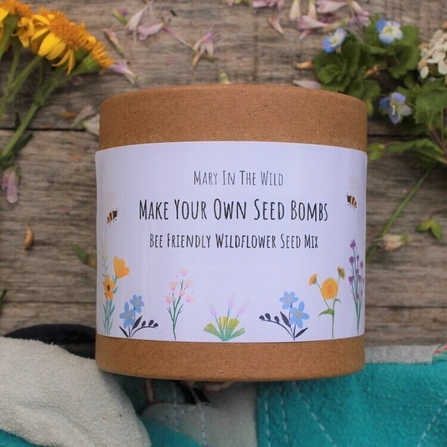 Wildflower seed bomb kit on a wooden table alongside wildflowers.