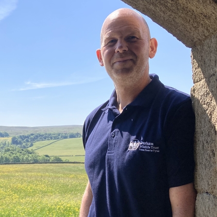 Mark Dinning standing in barn door at Hannah's Meadow with flower meadow in background