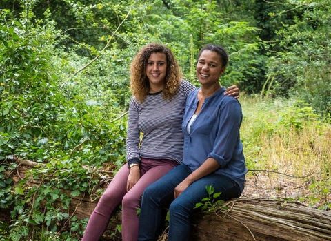 Juliet and Amy sit together on a fallen tree