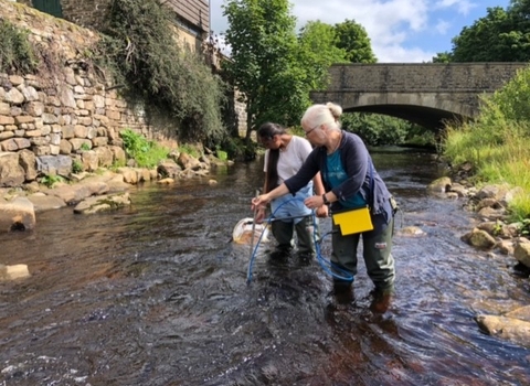 Two women sampling the water in the River Wear for plastic